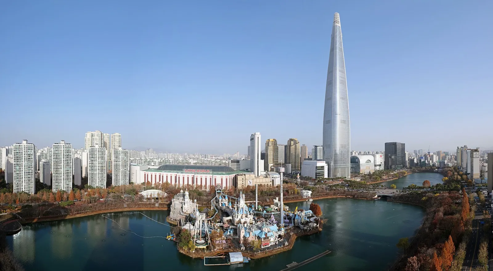 The Lotte World complex across Seokchon Lake: Magic Island in front and the long Adventure building behind it, which holds the ice rink on its third basement floor (2022). — Lotte World Ice Rink