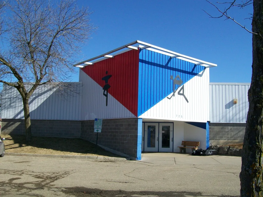Madison Ice Arena desde su estacionamiento en un día soleado y sin nieve a finales del invierno — Madison Ice Arena