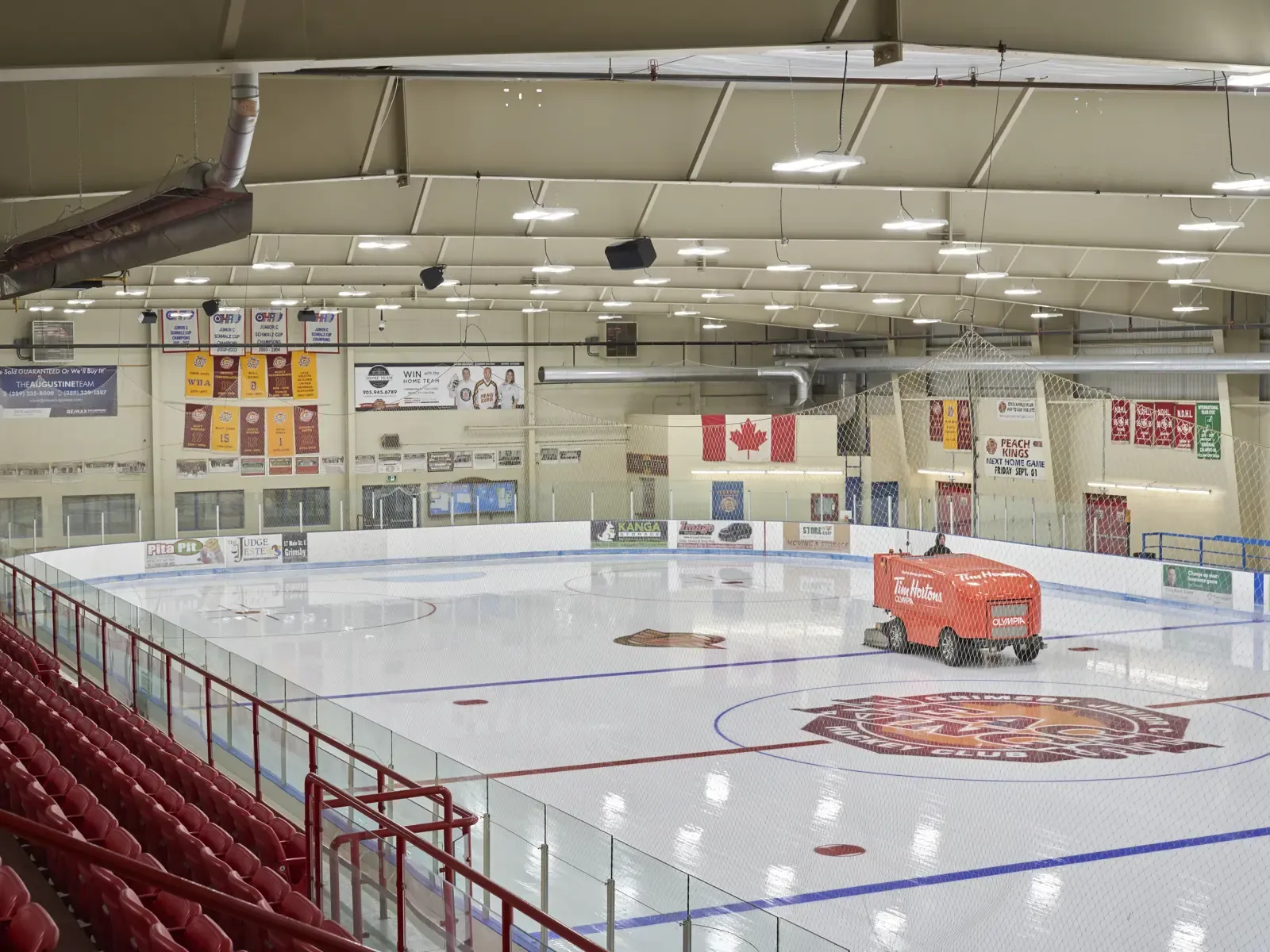 Una de las dos pistas de hielo vista desde las gradas, con una Zamboni sobre el hielo y banderines de los Peach Kings en la pared del fondo. — Major Refrigeration Peach King Centre