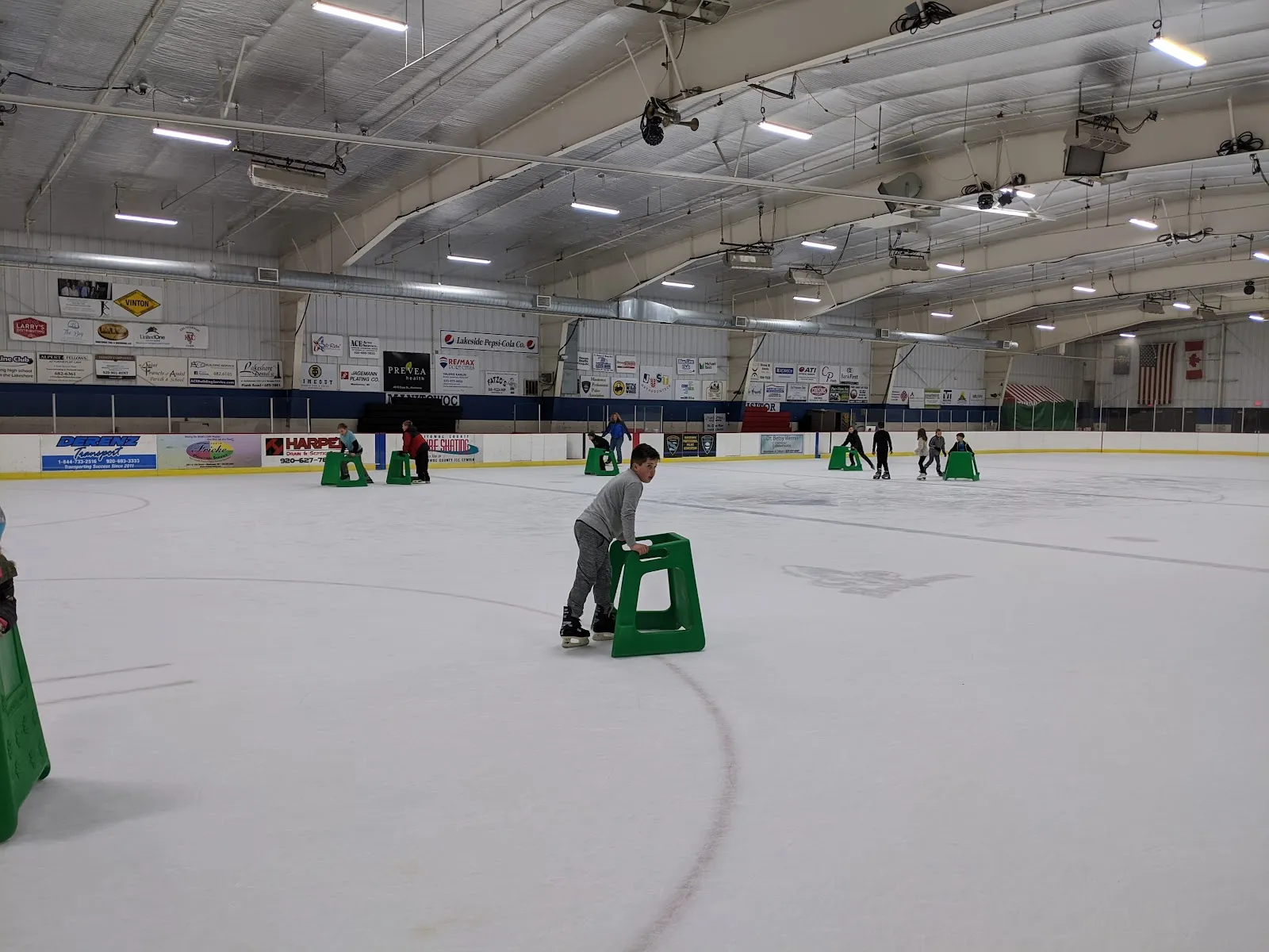Learner skaters with skating aids on the ice sheet at Manitowoc County Ice Center — Manitowoc County Ice Center