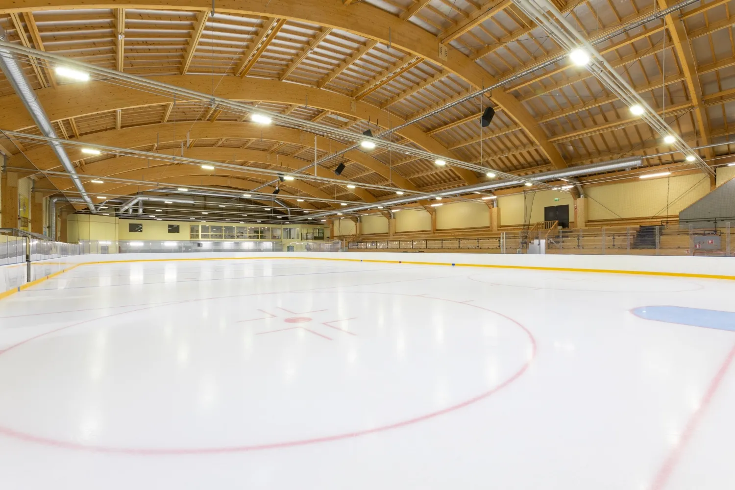 The ice sheet inside the Mäntsälä ice hall under its curved timber roof – Mäntsälän Jäähalli