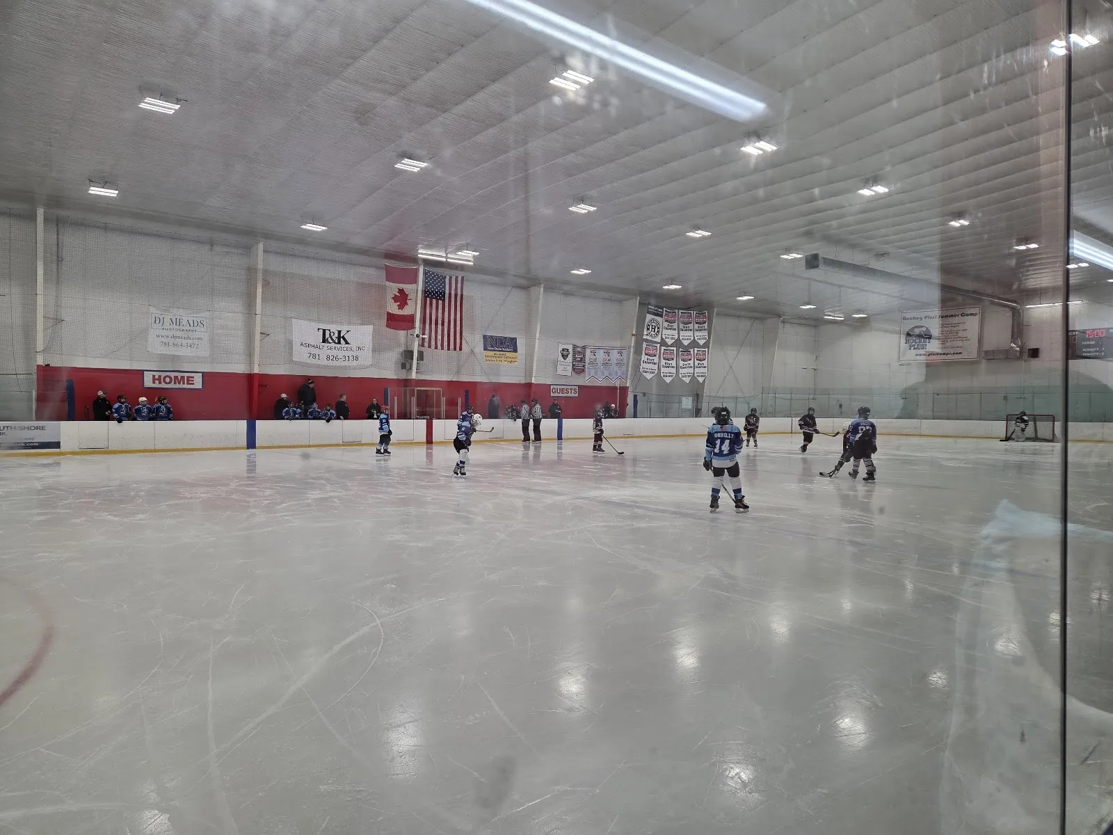 A wide view across the Mark Bavis Arena ice with a few players scattered far down the rink and the boards along the side. — Mark Bavis Sports Complex