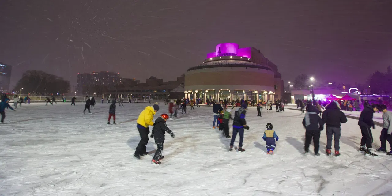 Skaters on the outdoor rink at Markham Civic Centre at night, with the lit dome of the Civic Centre behind the ice. — Markham Civic Centre Outdoor Ice Rink