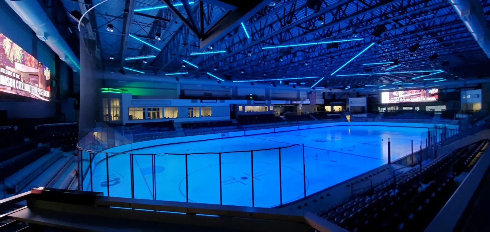 The ice sheet of Mason City Arena seen from the seating bowl, with large video boards and blue arena lighting. — Mason City Arena
