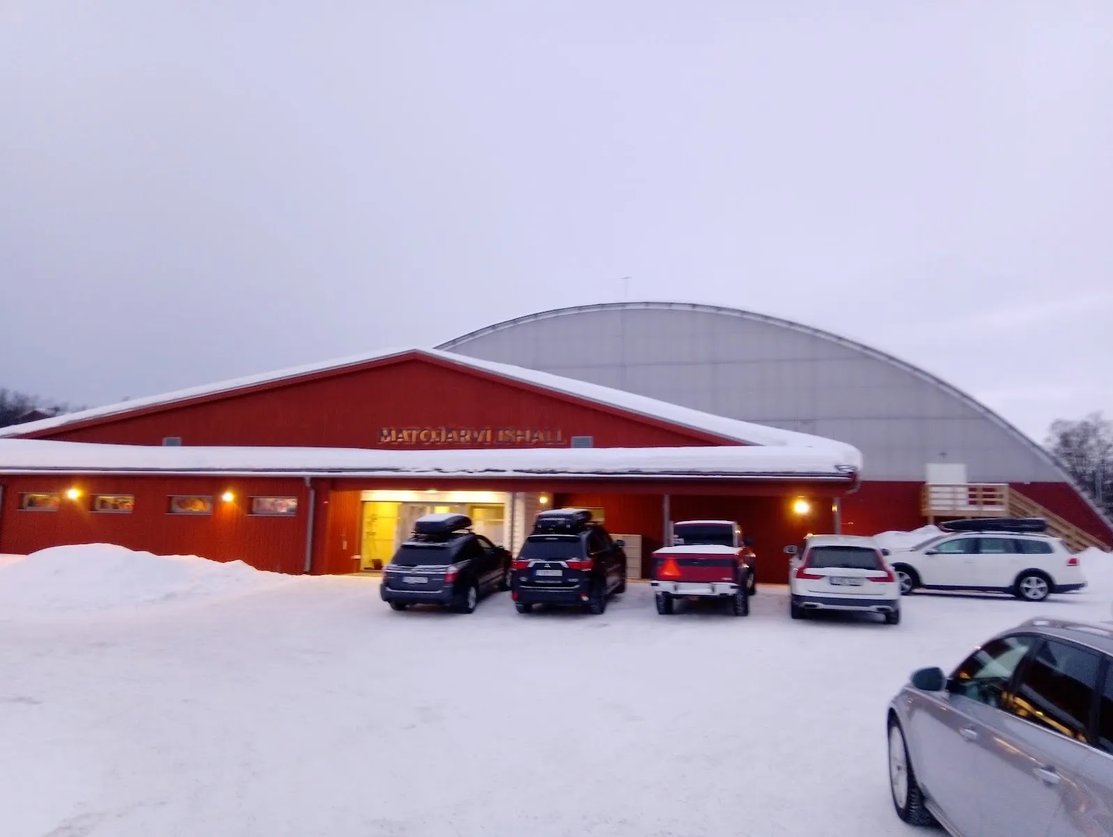 The red Matojärvi ishall building in the snow with the curved roof of the hall behind it – Matojärvi ishall (Kiruna)