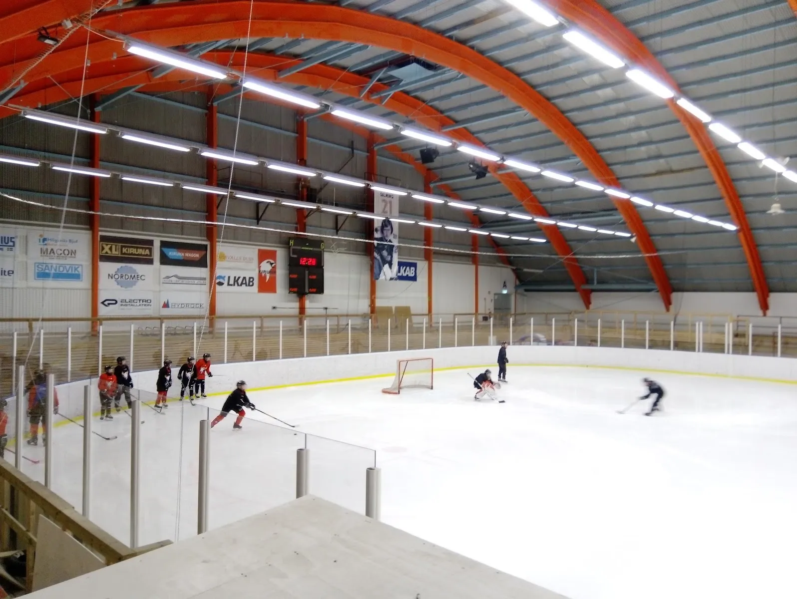 Ice hockey practice on the ice of Kiruna ishall Matojärvi, seen from the stand under the red arched roof beams – Matojärvi ishall (Kiruna)