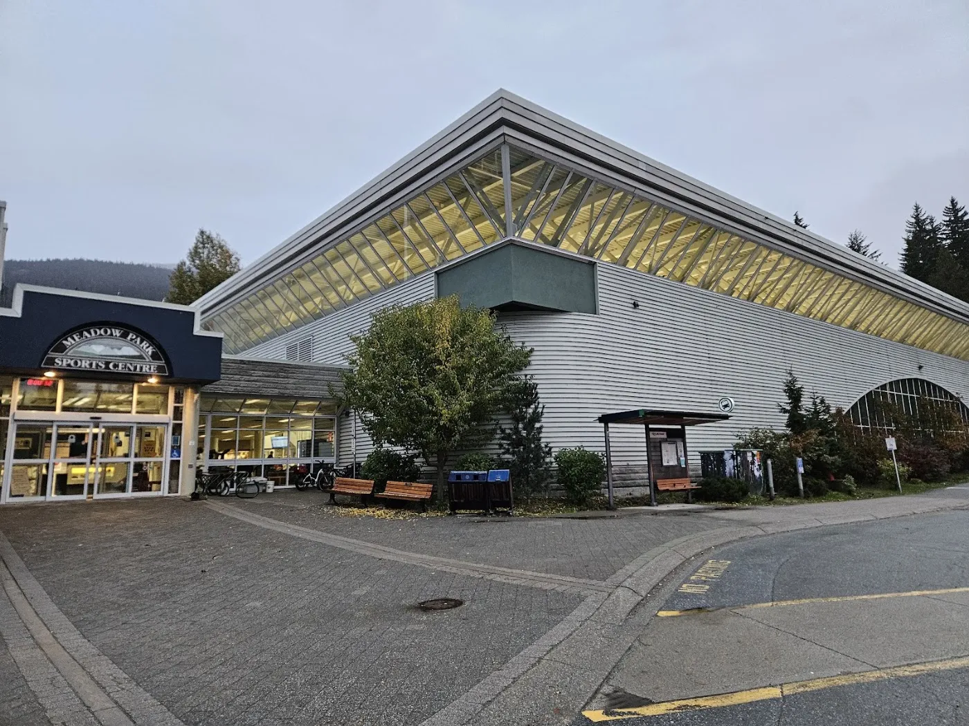 The street side of Meadow Park Sports Centre with its entrance sign and pitched glass roof. — Meadow Park Sports Centre