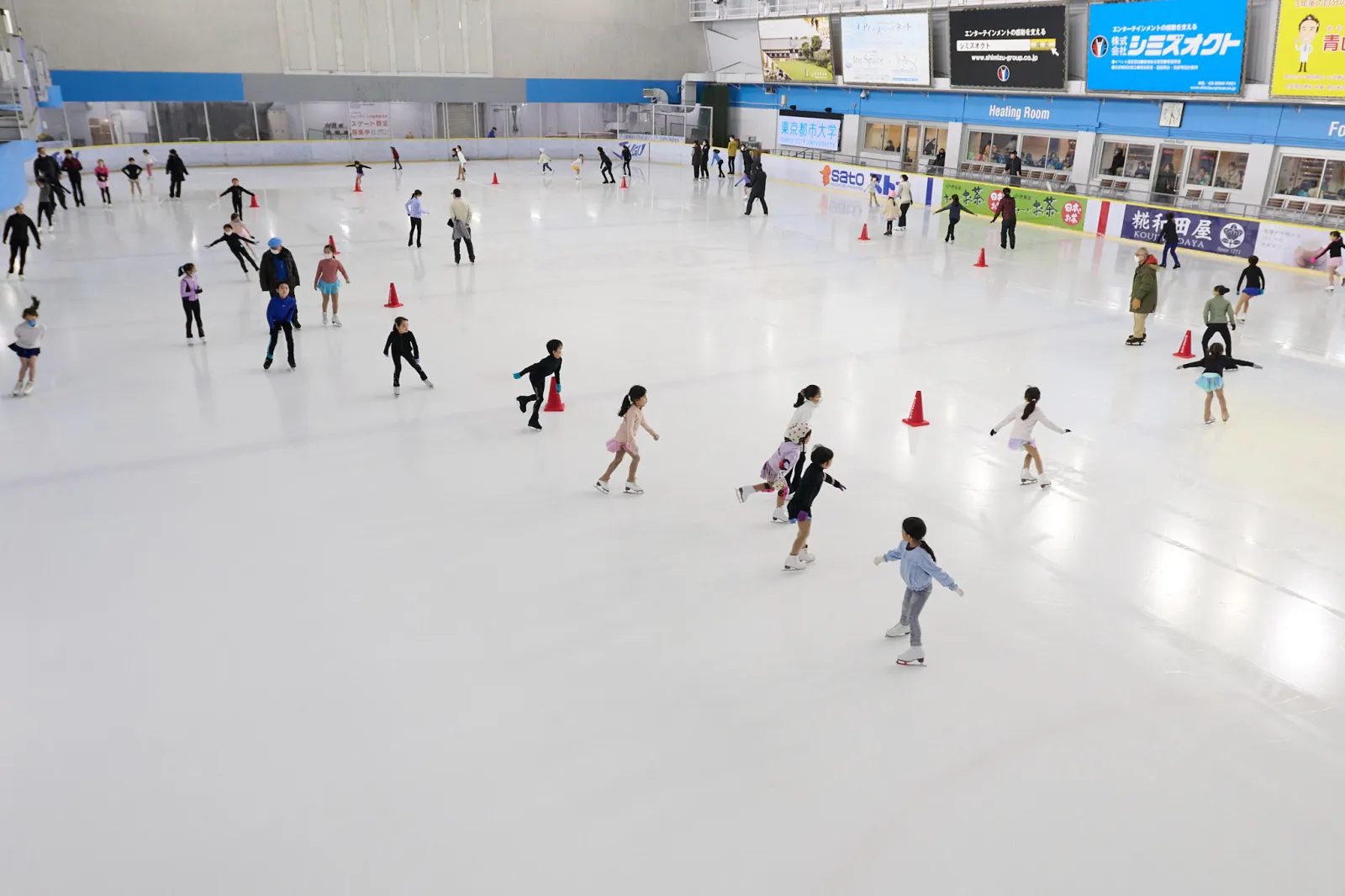 The wide ice surface of the Meiji Jingu Gaien rink during a public session, seen from the end of the rink — Meiji Jingu Gaien Ice Skating Rink