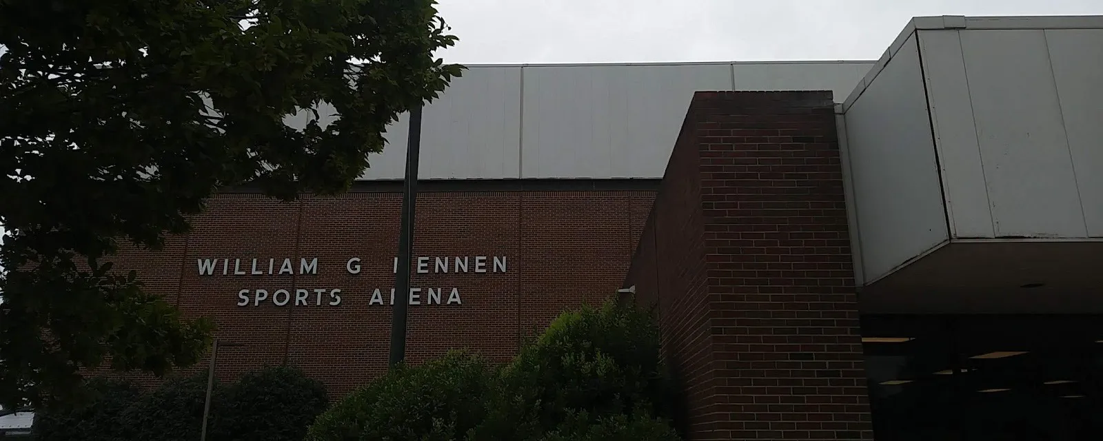 La fachada de ladrillo del William G. Mennen Sports Arena con su nombre en letras metálicas, junto a la entrada principal con marquesina — William G. Mennen Sports Arena