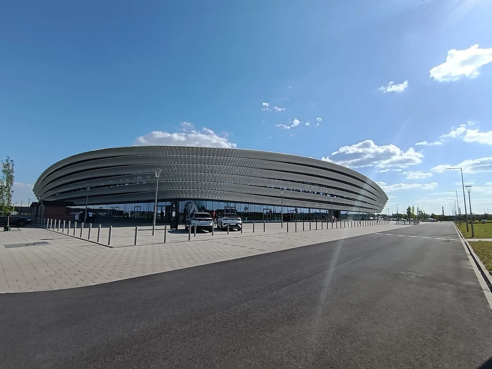 Az ovális, fémburkolatú MET Aréna épülete és előtere – MET Aréna Székesfehérvár