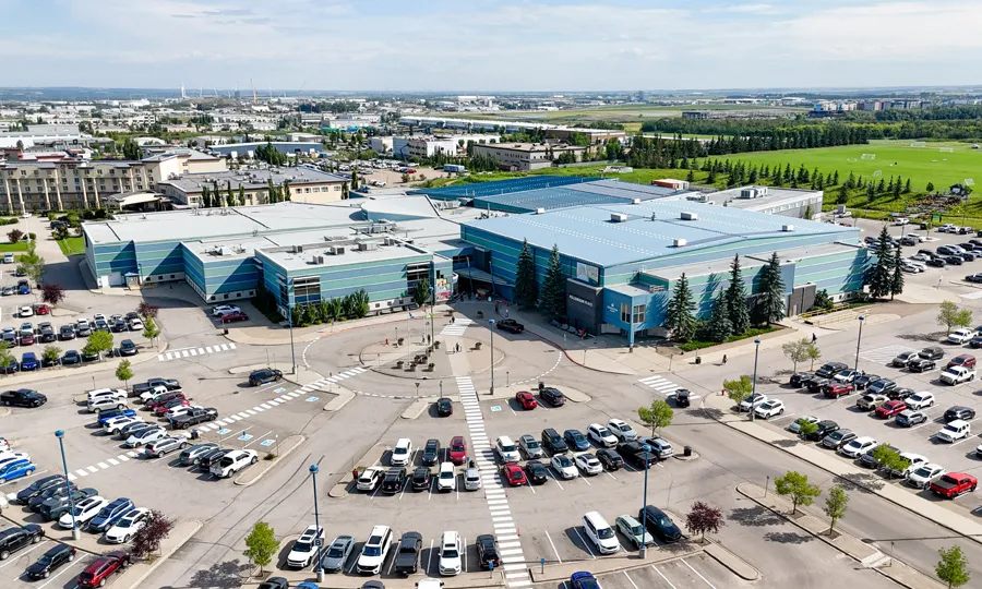 Millennium Place desde el aire: el largo centro recreativo de techo azul detrás de sus estacionamientos, con Sherwood Park al fondo. — Millennium Place