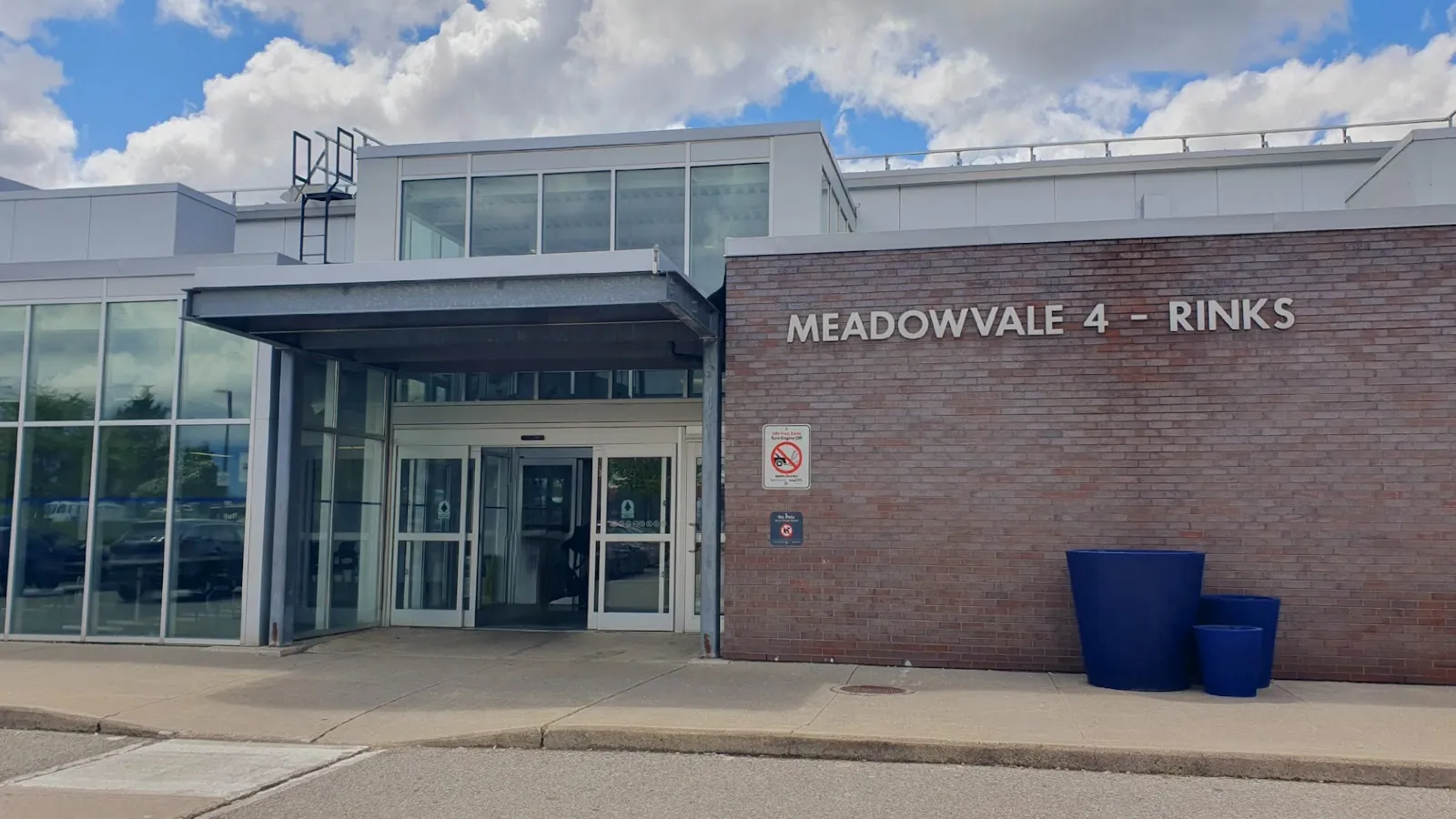 La entrada de Meadowvale 4 Rinks, un muro de ladrillo con el nombre de la arena junto a un vestíbulo de vidrio bajo una marquesina de acero — Meadowvale 4 Rinks