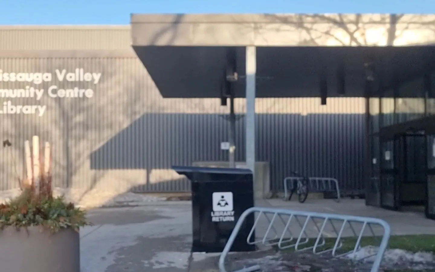 La entrada de Mississauga Valley Community Centre, con su nombre en letras sobre un revestimiento gris acanalado junto a una marquesina plana de acero — Mississauga Valley Community Centre Arena