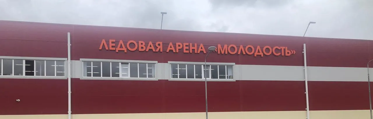 The ice arena's red and cream facade with its Ледовая арена Молодость sign — Molodost Ice Arena Krasnouralsk