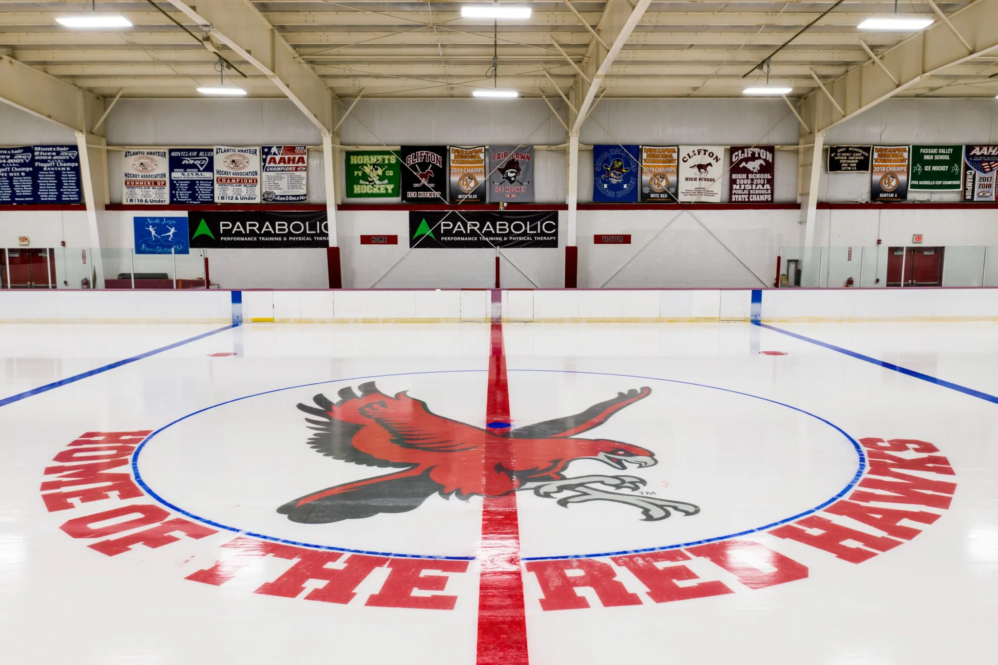 Centre ice at Montclair State Arena, painted with the red-and-grey Red Hawk crest and Home of the Red Hawks lettering — Montclair State Arena