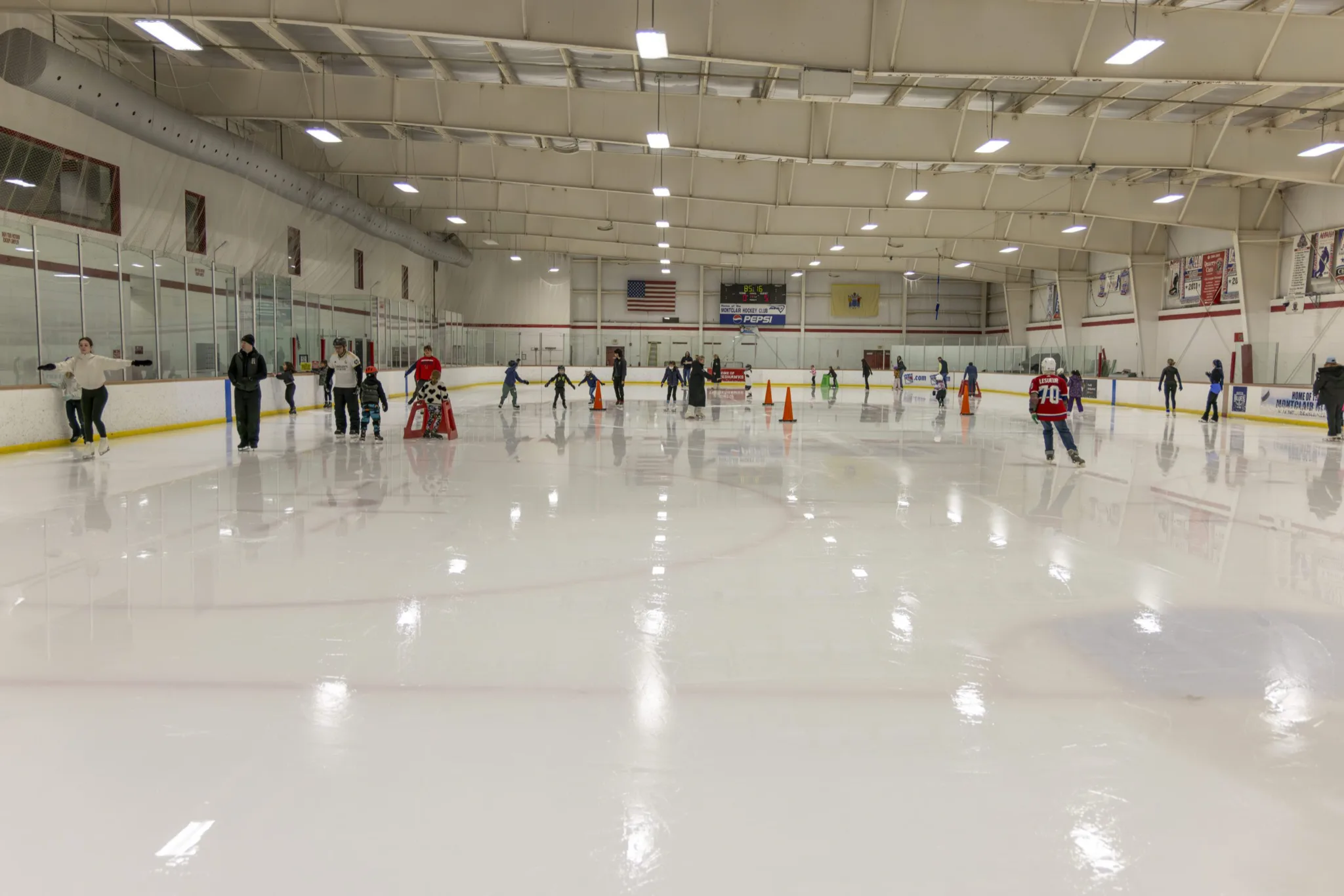 Learn-to-skate session with orange cones spread across nearly the whole sheet at Montclair State — Montclair State Arena
