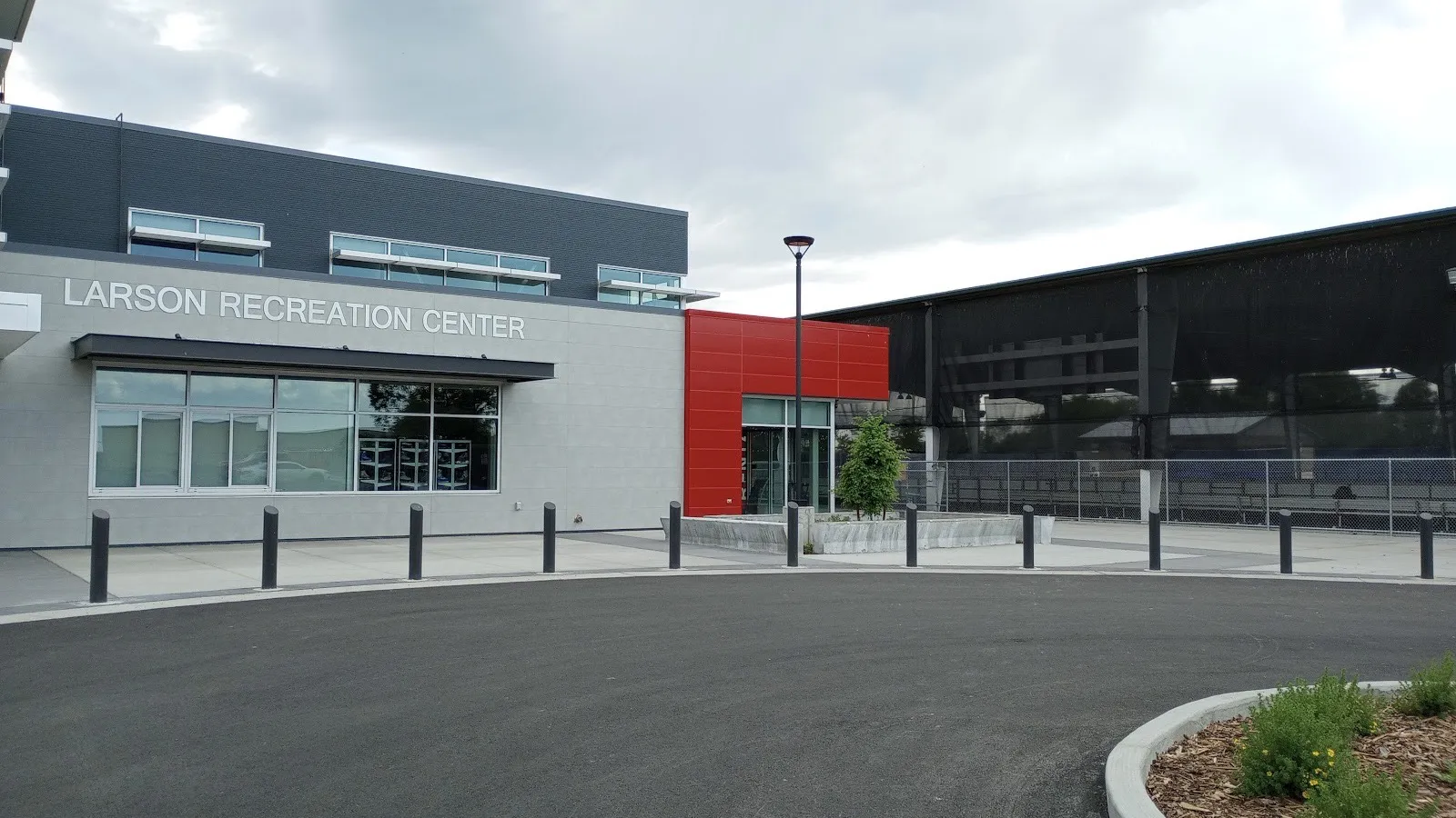 The Larson Recreation Center with the covered outdoor ice rink beside it, its boards visible through the black mesh walls — Moses Lake Ice Rink