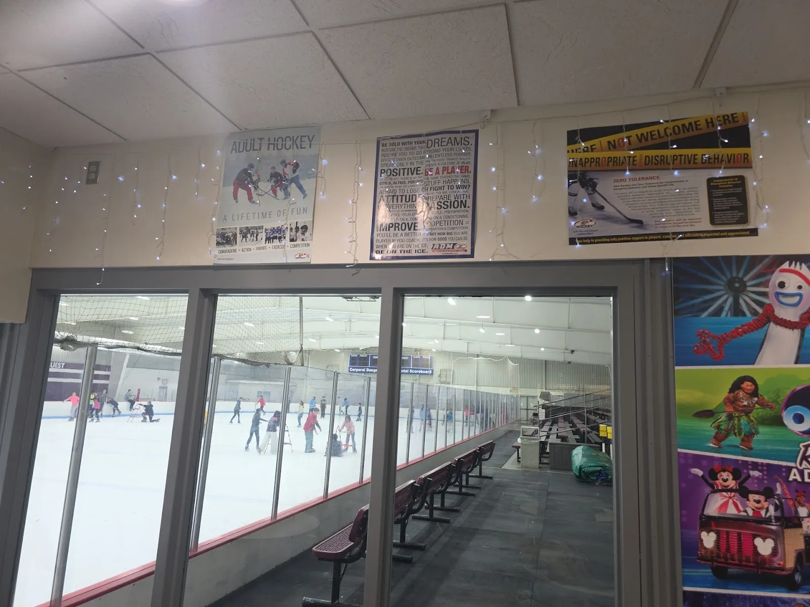 A public session on the ice seen from the viewing windows, skaters at a distance — Motto McLean Ice Arena