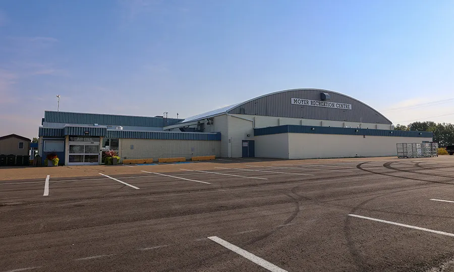 The barrel-roofed Moyer Recreation Centre, signed along its front, across an empty parking lot. — Moyer Recreation Centre