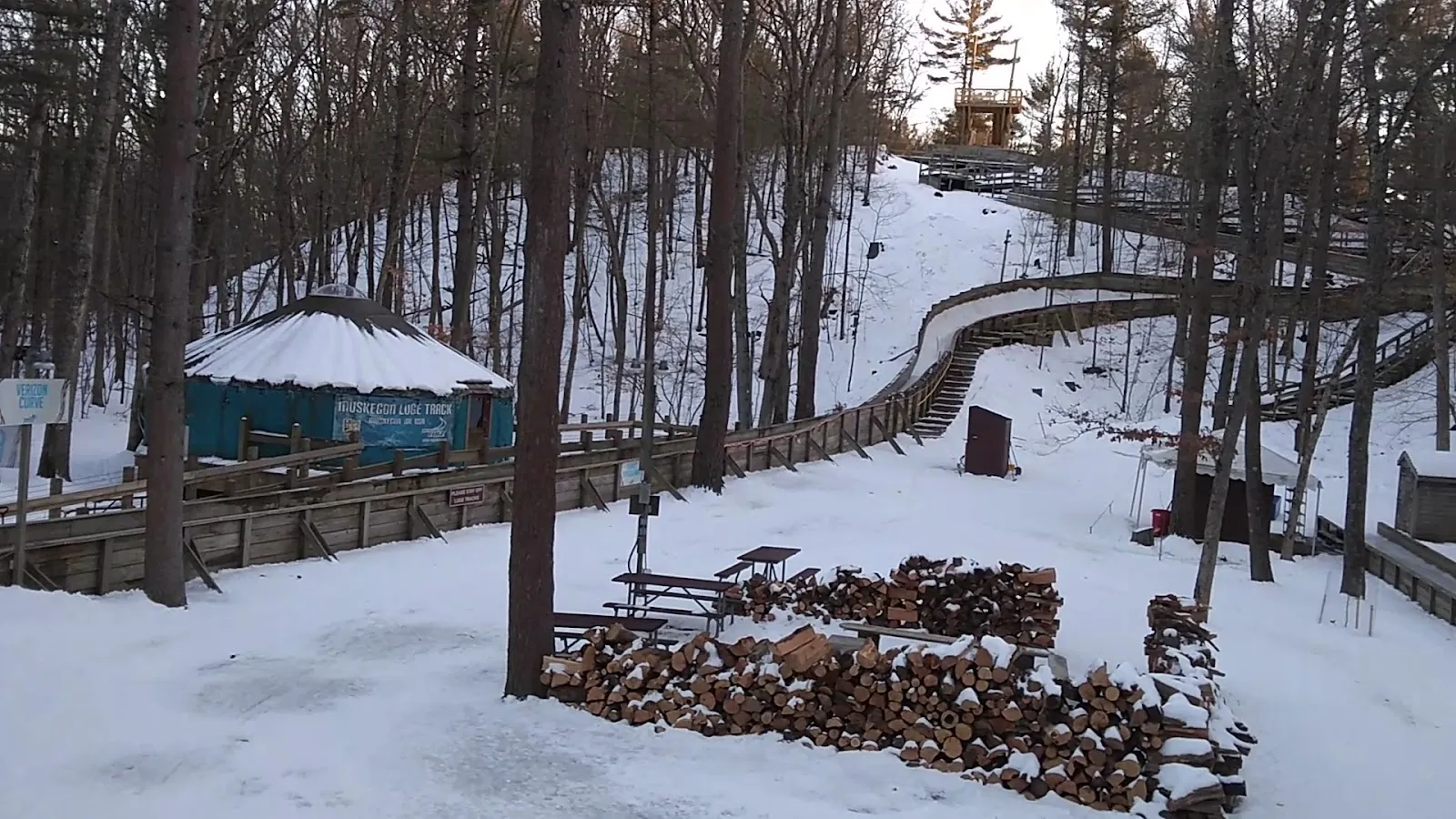 The warming yurt, firewood and the luge track on the wooded hillside at Muskegon Luge Adventure Sports Park — Muskegon Luge Adventure Sports Park Ice Rink