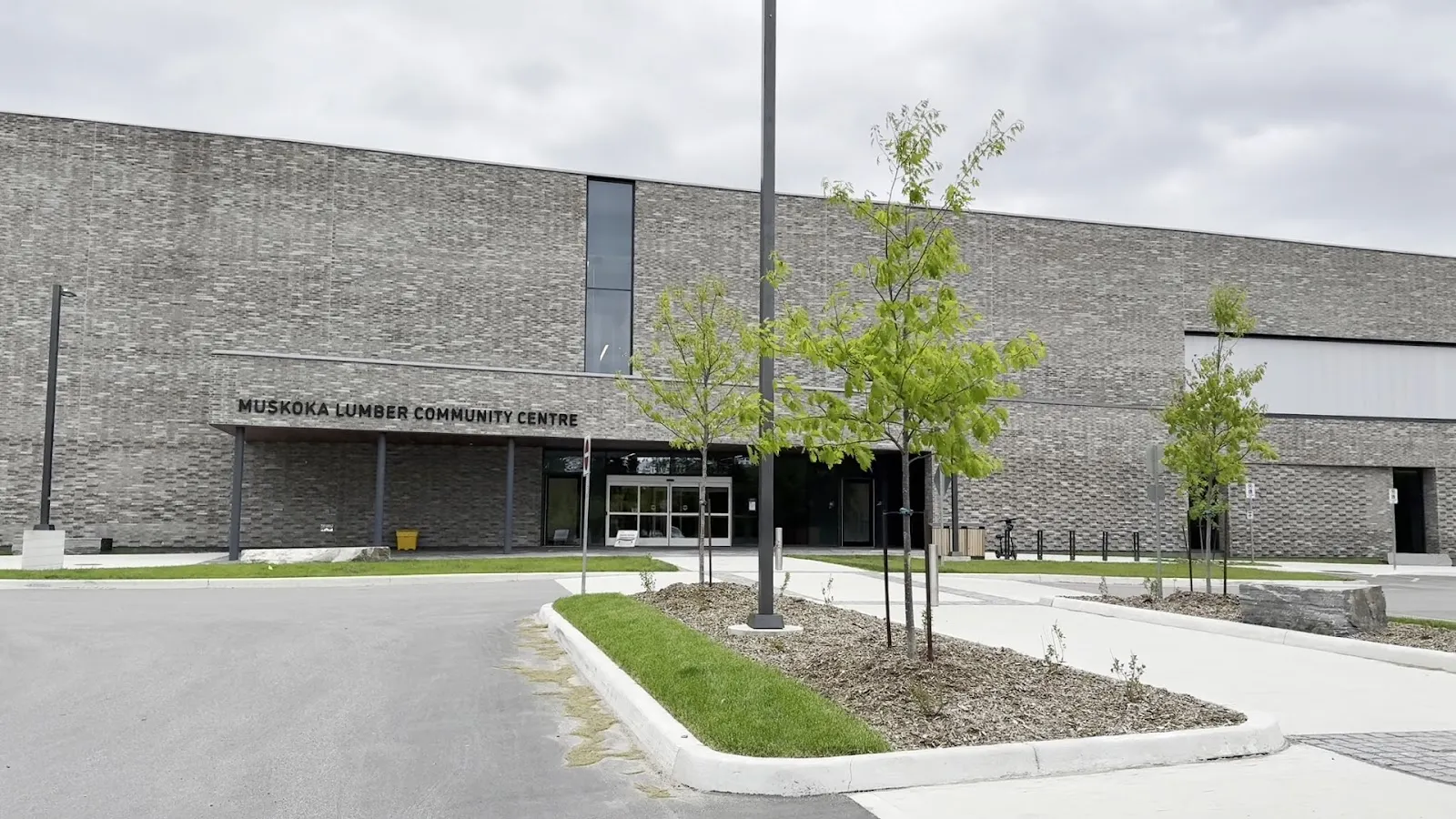 The grey brick front of the Muskoka Lumber Community Centre with its lettered sign over the entrance. — Muskoka Lumber Community Centre (Bracebridge)