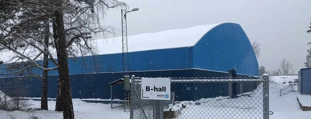 The blue Nacka istält in the snow, with a B-hall sign on the fence in front — Nacka istält