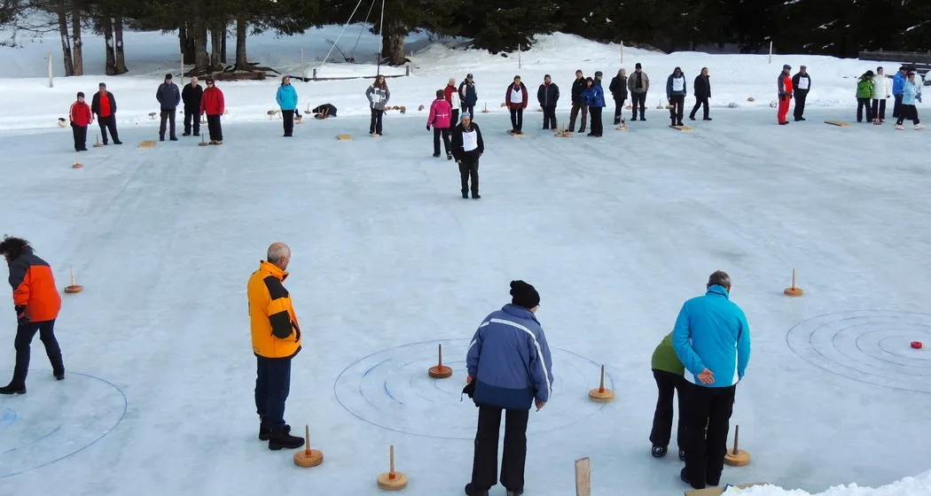 Players spread across the snow-covered natural ice field at Oberurmein during an ice-stock game — Natureisfeld Oberurmein