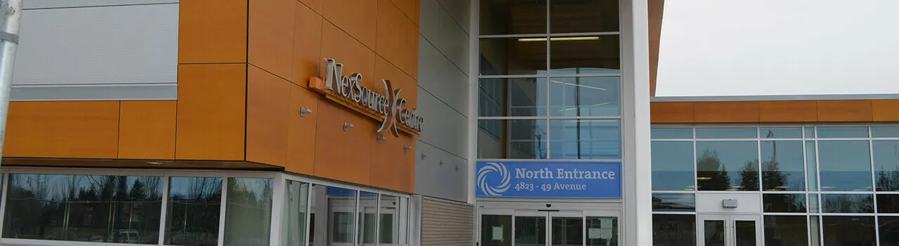 The NexSource Centre north entrance: orange panelled wall with the NexSource Centre lettering and a glass entry under a blue North Entrance sign. — NexSource Centre