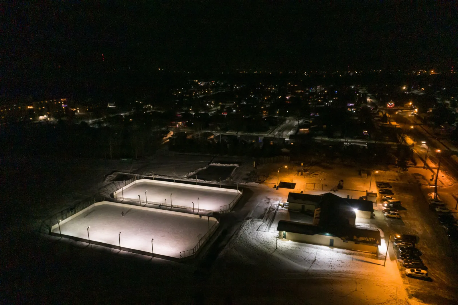 Vista aérea de las pistas del North End Community Centre junto al edificio del centro y su estacionamiento — North End Community Centre Outdoor Rinks