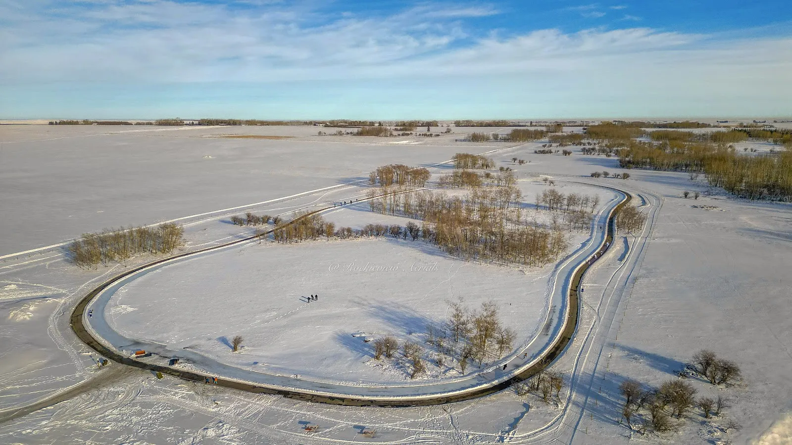 Vista aérea del circuito ovalado de patinaje helado entre bancos de nieve a través de los campos abiertos de Northeast Regional Park. — Northeast Regional Park Snowbank Rink (Airdrie)