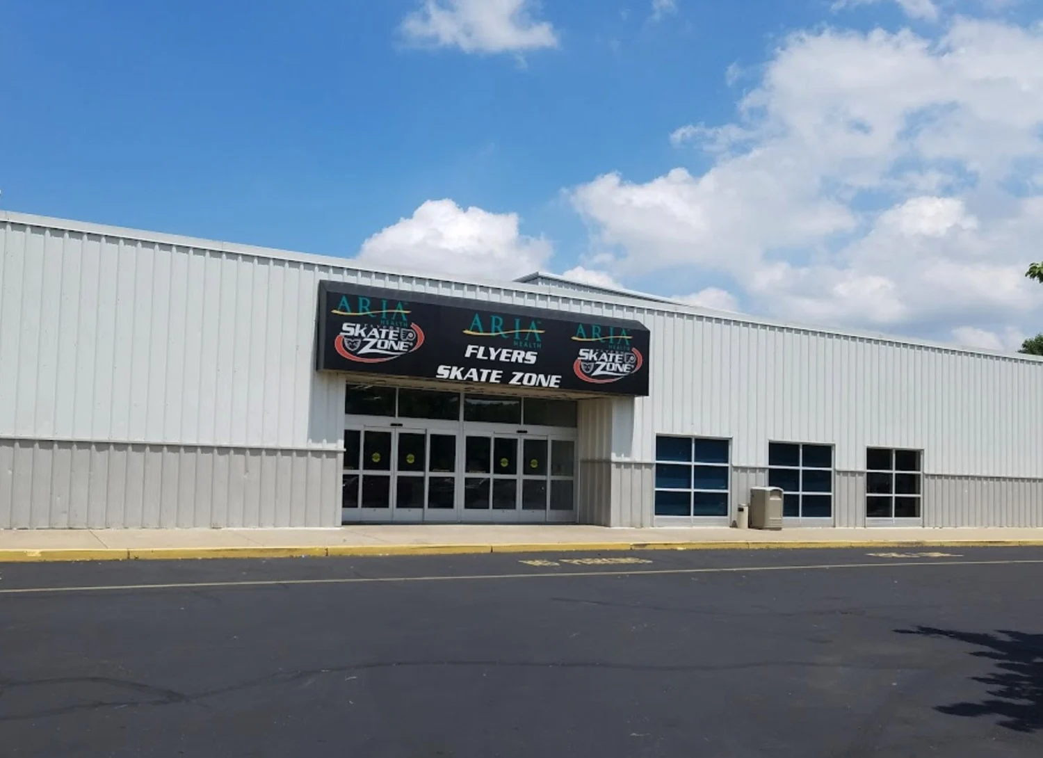 Northeast Skate Zone's silver facade and entrance under the Skate Zone sign. — Northeast Skate Zone