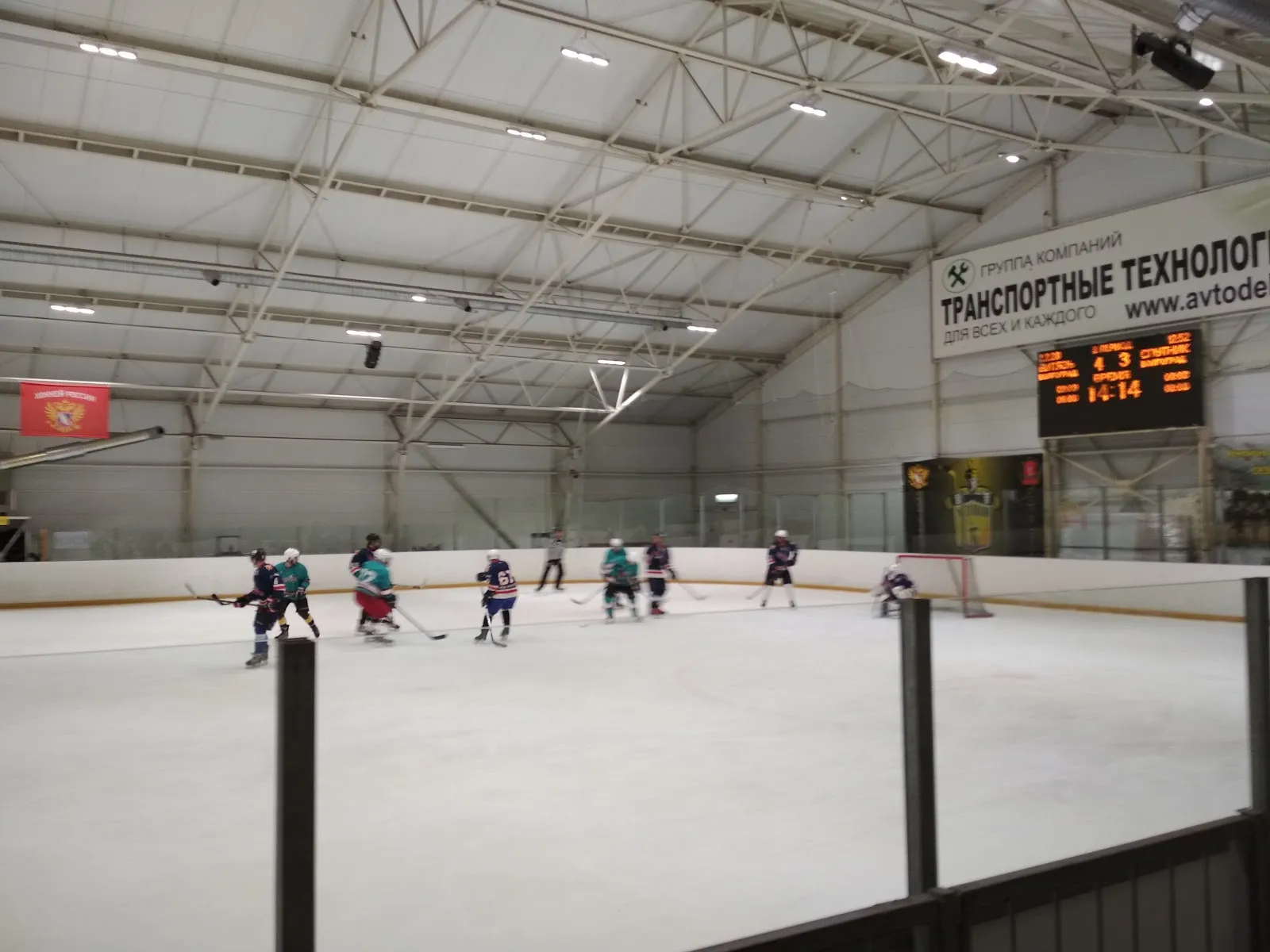 A youth game on the ice of Novoye Pokoleniye in Volgograd, players at the far end under the roof lights — Novoe Pokolenie Ice Rink Volgograd