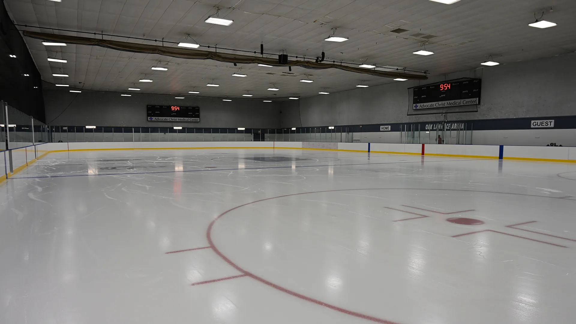La pista vacía y recién pulida, con la banca de visitantes al fondo — Oak Lawn Ice Arena