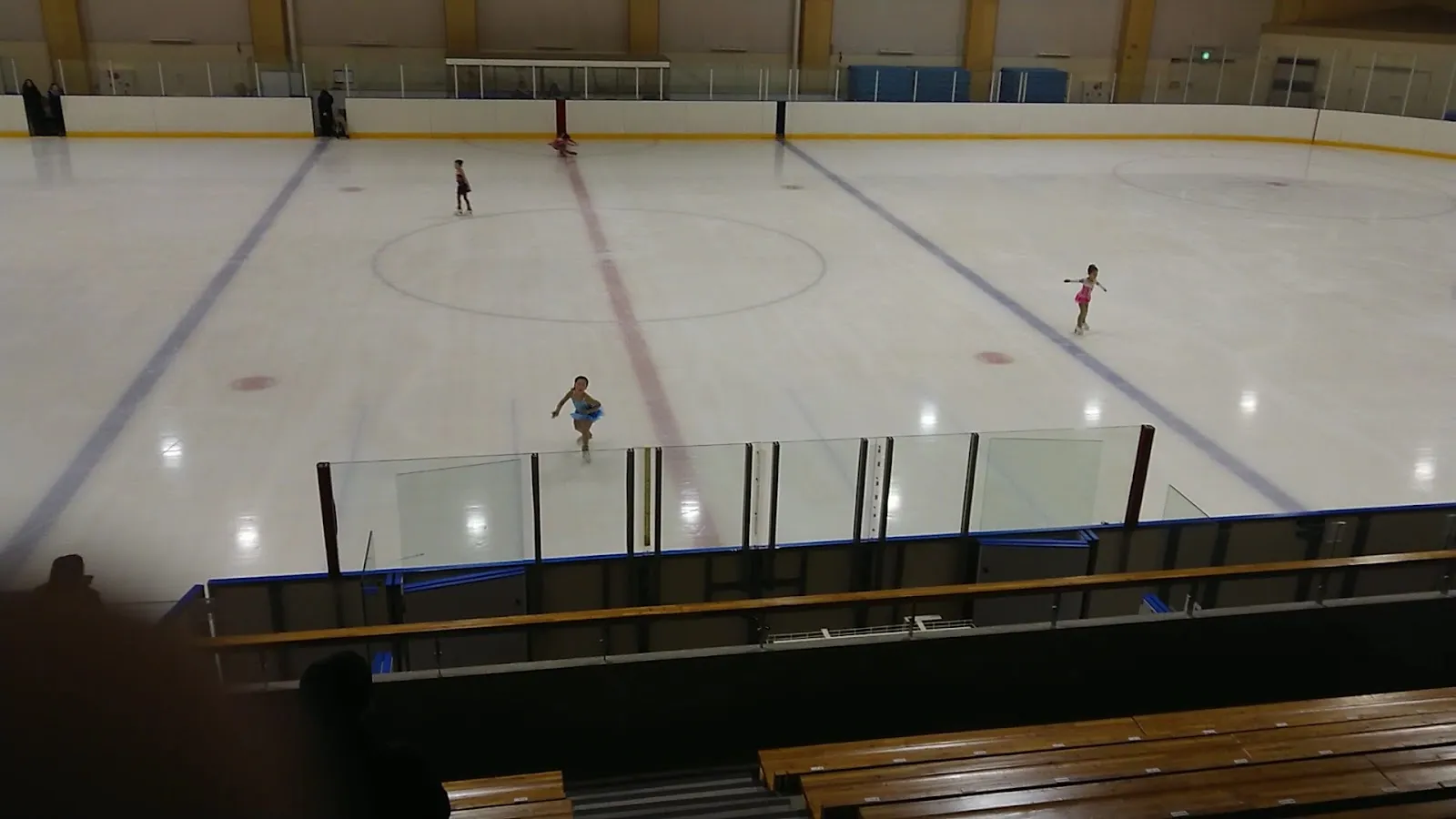 客席から見た帯広の森スポーツセンターの氷。遠くに数人のスケーターがいて、氷の上にセンターサークルが引かれている。 — Obihiro Forest Sports Center