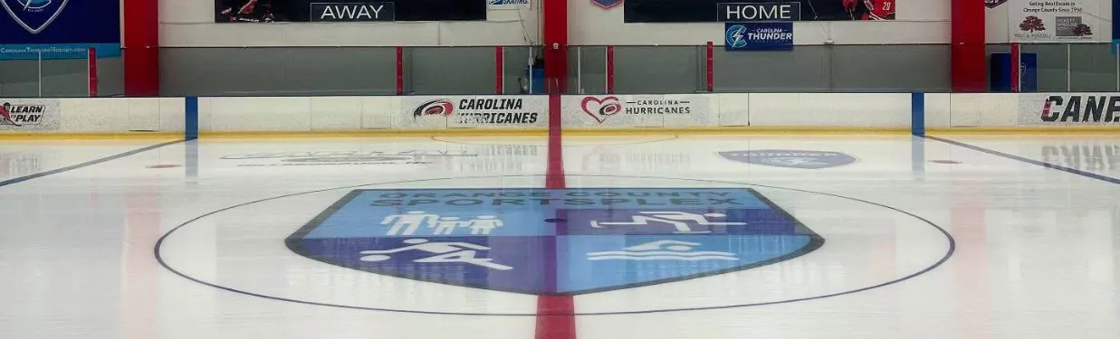 Center ice with the Orange County Sportsplex logo and red line, Carolina Hurricanes dasher-board ads, and a Carolina Thunder sign above the glass. — Orange County Sportsplex