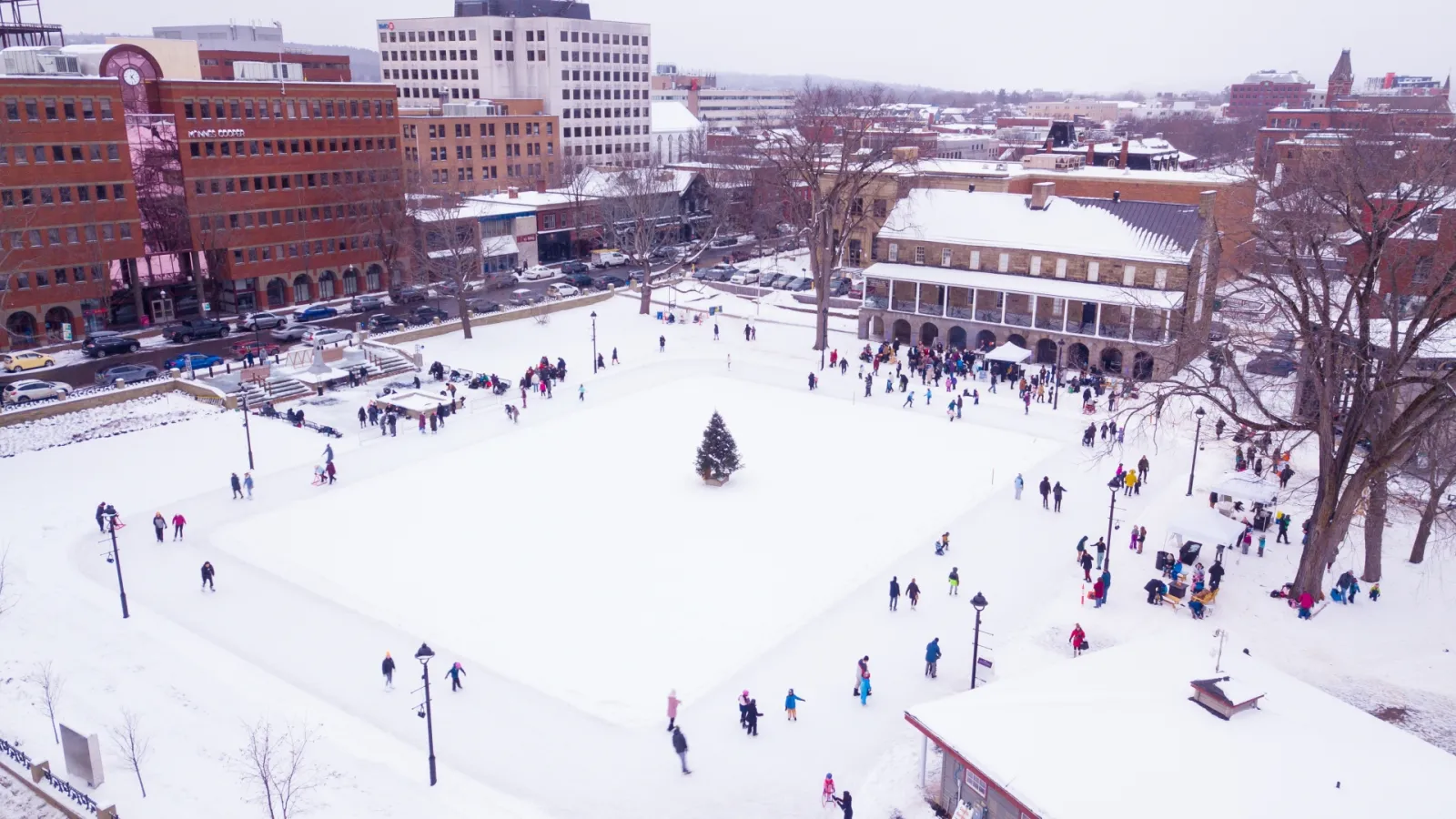 Skaters on the Officers' Square outdoor rink in downtown Fredericton, seen from above with the Garrison buildings behind — Officers' Square Outdoor Rink