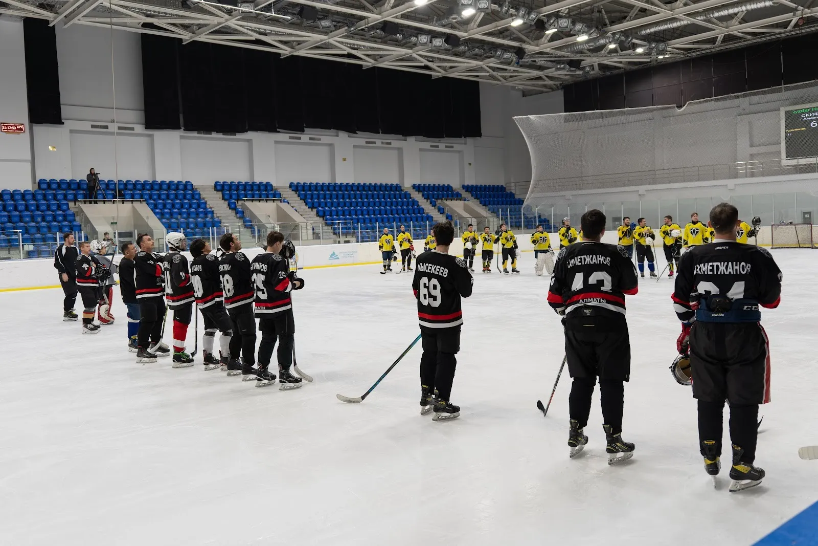 Hockey teams lined up on the ice at Olimpic Arena before a game, with the stands behind — Olimpic Arena