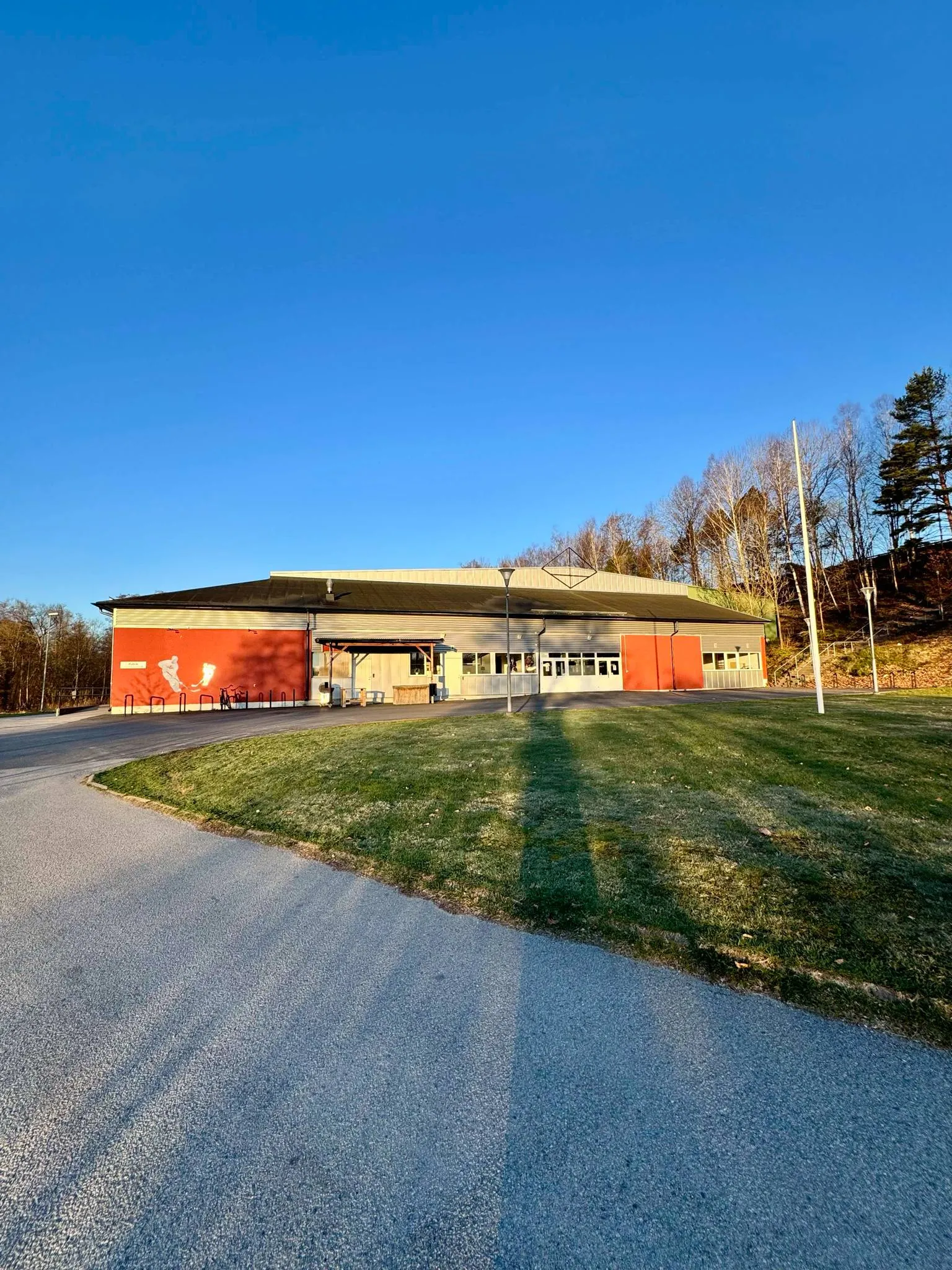 The low red-ended Olofströms ishall building seen from the road under a clear sky — Olofströms ishall