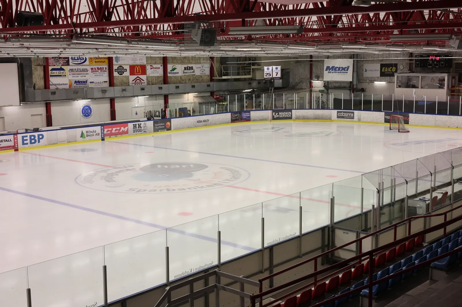 The empty ice of Olofströms ishall seen from the corner of the stands, under the red steel roof — Olofströms ishall