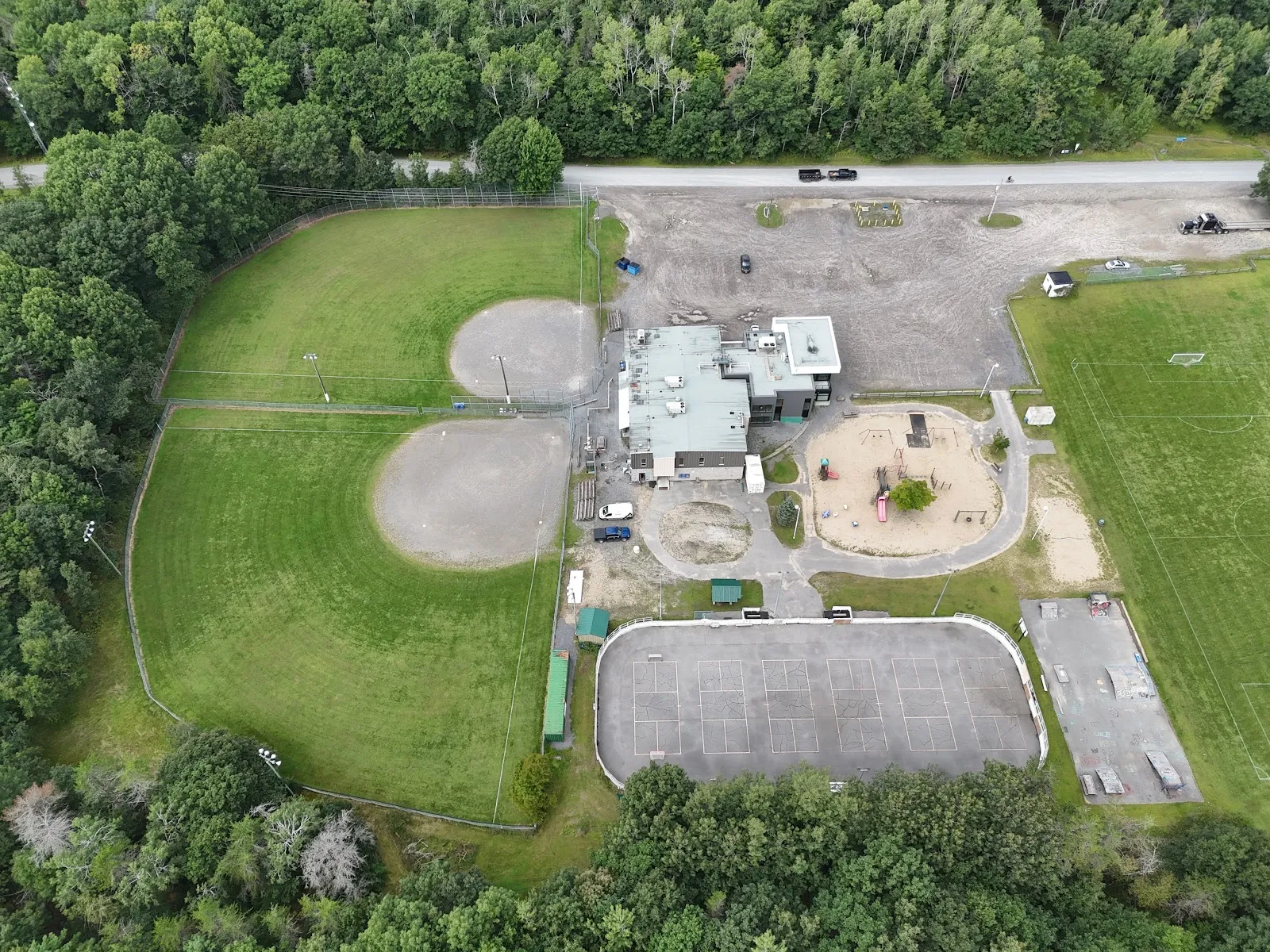 Vista aérea de los terrenos del centro comunitario de Constance Bay, con campos de beisbol, el área de juegos y la plataforma de la pista con vallas. — Constance Buckham's Bay Community Centre Park Outdoor Rink