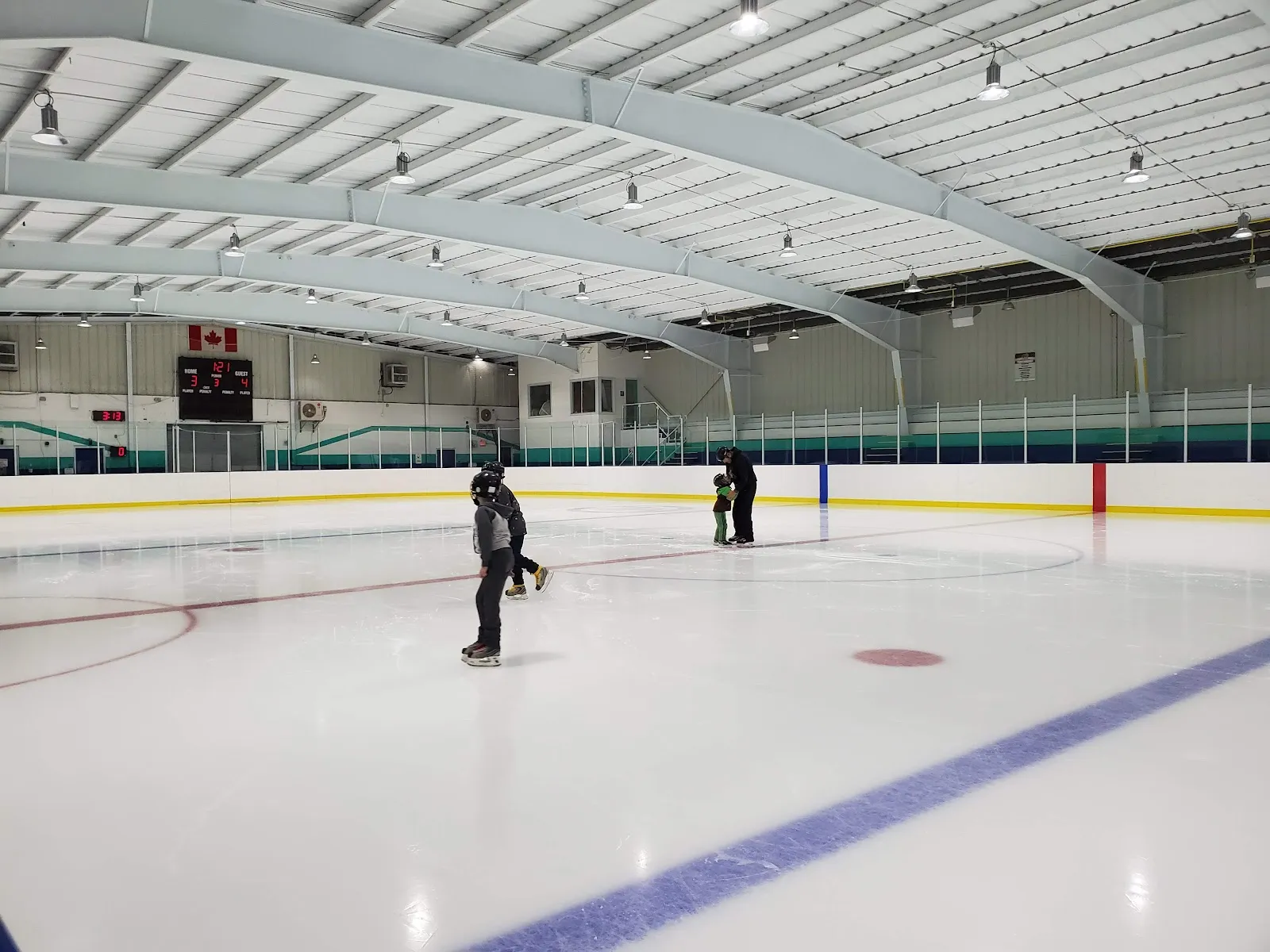 Interior de la arena con toda la pista, las vallas, un marcador con una bandera de Canadá arriba y algunos patinadores en el hielo. — Lois Kemp Arena (Blackburn)