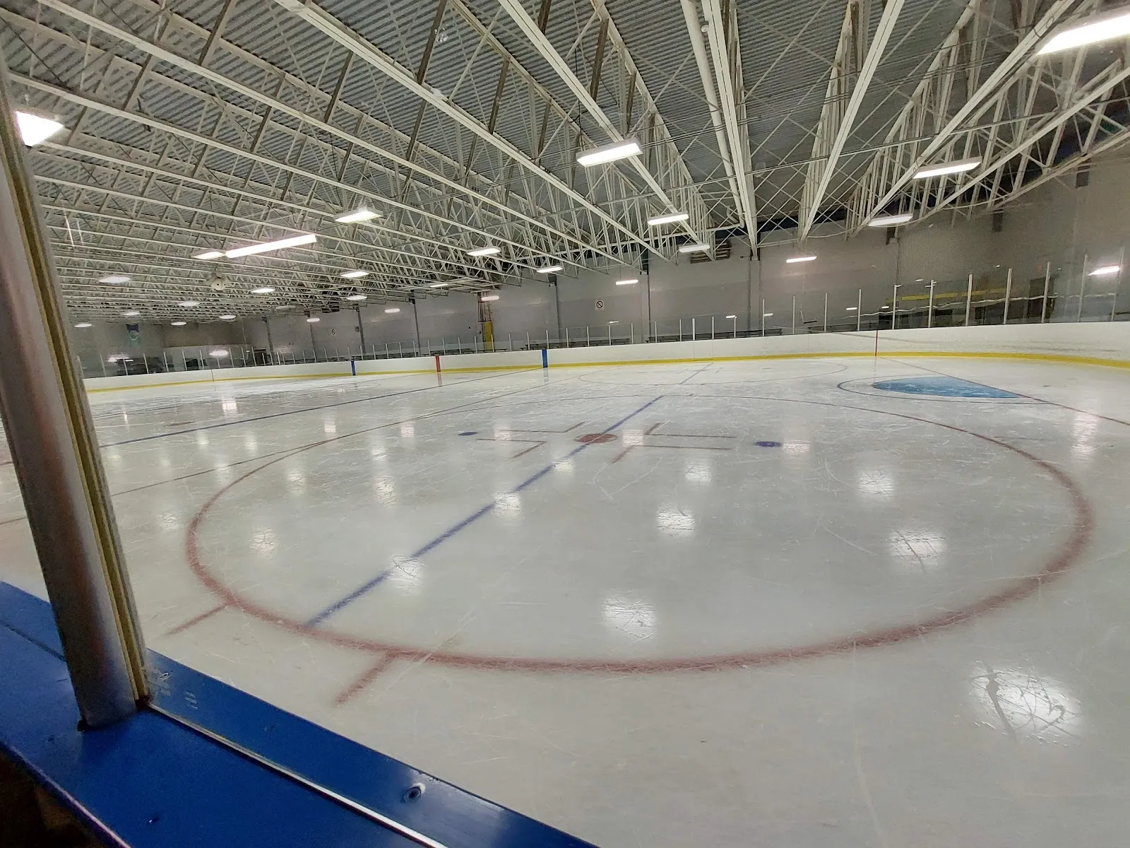 The McNabb Arena ice under its steel roof, with a red faceoff circle in the foreground. — McNabb Arena and Community Centre