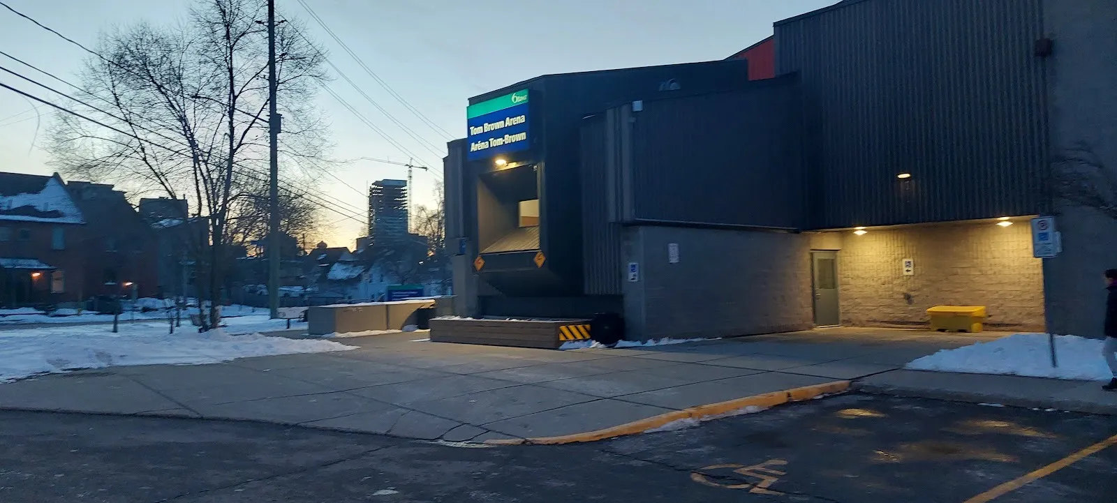 The Tom Brown Arena on Bayview Station Road in Ottawa at dusk, with its lit City name sign above the entrance — Tom Brown Arena