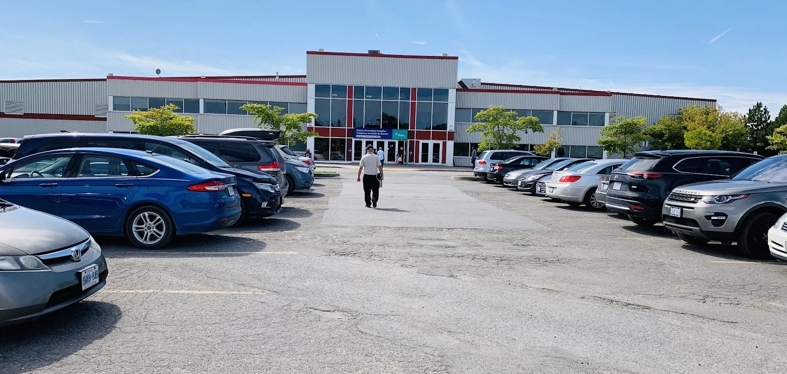 The Tony Graham Recreation Complex in Kanata, with its red-trimmed glass entrance centred across the front parking lot — Tony Graham Recreation Complex – Kanata