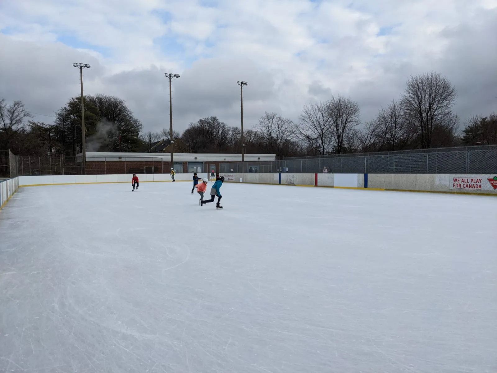 Wide view of the Otter Creek outdoor rink ice and boards under an overcast sky — Otter Creek Centre Outdoor Ice Rinks