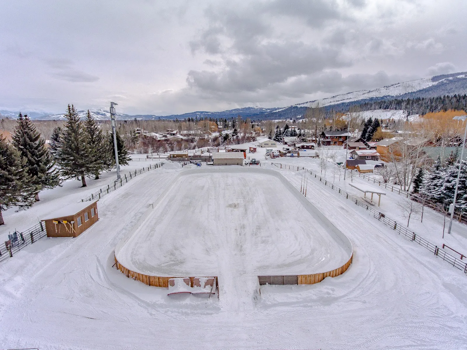 Aerial view of the snow-banked Owen Bircher Park rink with its wooden boards, in Wilson with the Tetons behind — Owen Bircher Park Rink