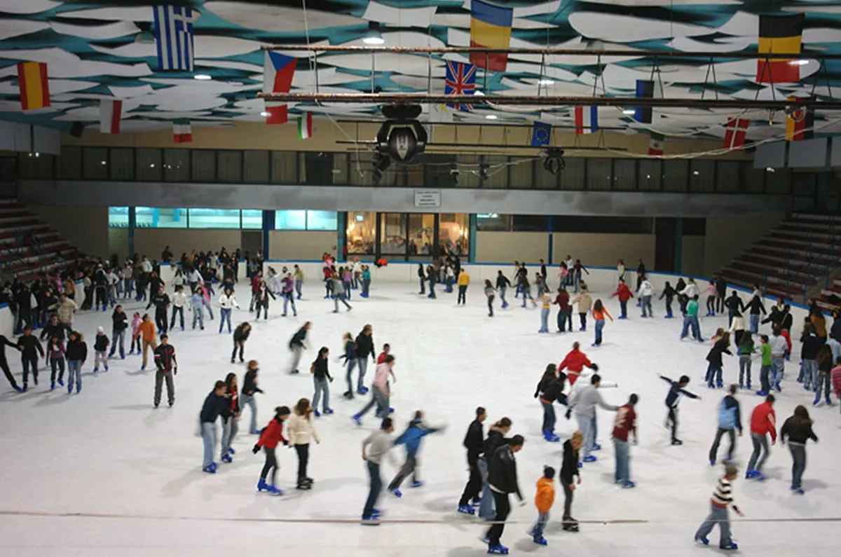 The Bari rink during a public session, a crowd of skaters across the whole ice under a roof hung with national flags. — Palaghiaccio Di Palma