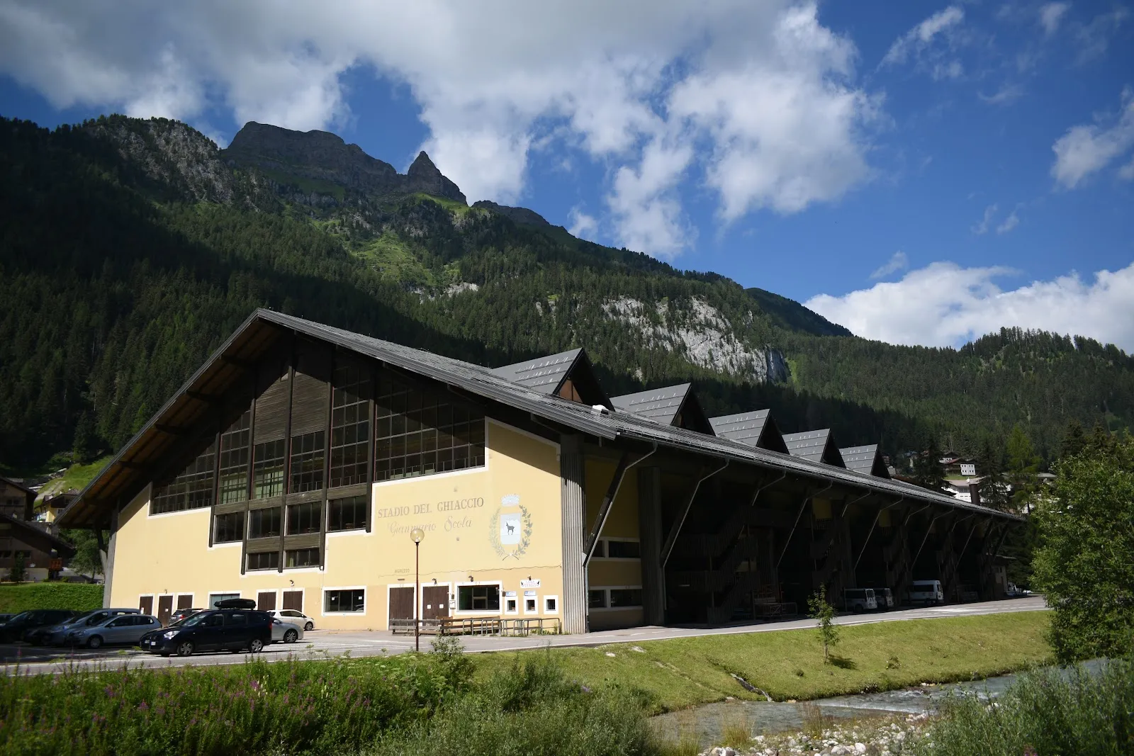 The Palaghiaccio Gianmario Scola in Alba di Canazei, a long timber-roofed hall under the Dolomites — Palaghiaccio Gianmario Scola
