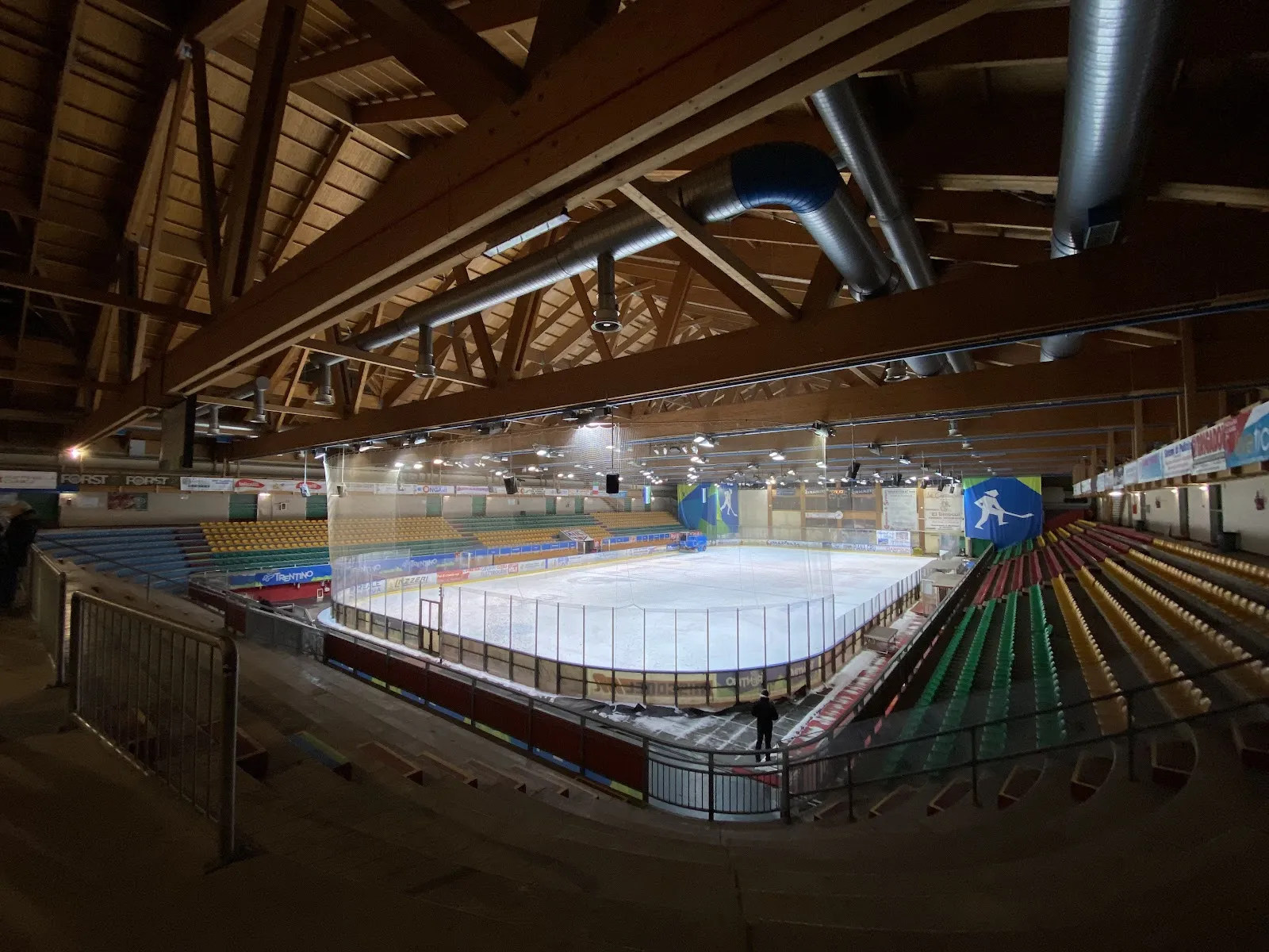 The arena's ice sheet and tiered seating under the wooden roof — Palaghiaccio Gianmario Scola