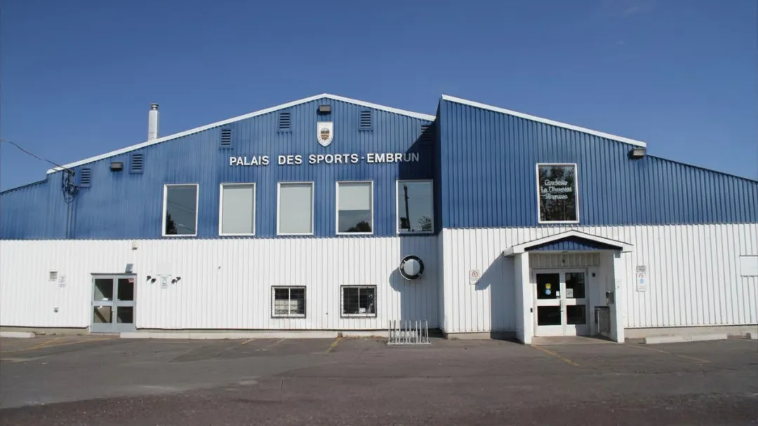 La fachada azul y blanca del Palais des Sports de Embrun, con su nombre a lo ancho del muro superior sobre la entrada. — Palais des Sports (Embrun Arena)
